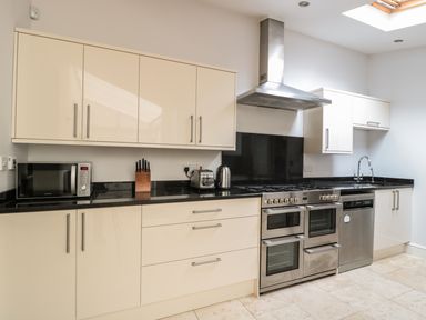 A kitchen with beige cabinets black countertops stainless steel appliances a microwave a knife block a toaster and kettle at 33 Crescent Gardens Bath