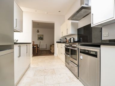 A kitchen with white cabinets stainless steel appliances and a dining area visible through an open doorway at 33 Crescent Gardens in Bath