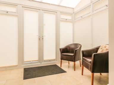 A room with two brown leather chairs a black mat and windows with closed blinds at 33 Crescent Gardens in Bath