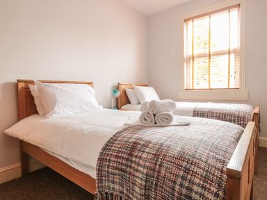 A bedroom with two single beds wooden bed frames with white bedding and blankets on the foot of beds at 33 Crescent Gardens in Bath