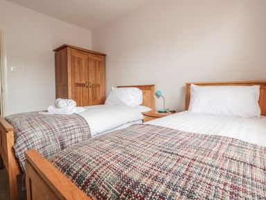 A bedroom with two single beds a wooden wardrobe and a nightstand at 33 Crescent Gardens in Bath