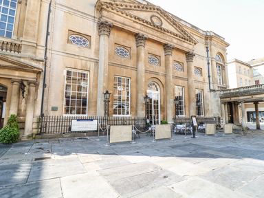The exterior of a historic building with large columns and outdoor seating at 33 Crescent Gardens in Bath
