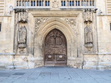 A large wooden arched door with stone carvings and statues on either side at 33 Crescent Gardens in Bath