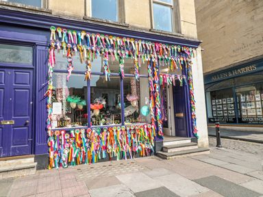 A shop front decorated with many colorful ribbons and rosettes on a street at 33 Crescent Gardens in Bath