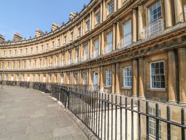 A curved row of historic buildings with multiple windows and black iron railings at 33 Crescent Gardens in Bath