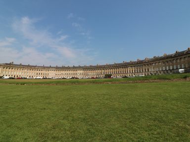 A large curved row of historic buildings with a grassy lawn in front at 33 Crescent Gardens in Bath