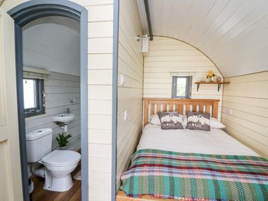 A bedroom with a wooden bed and a bathroom with a toilet and sink at Mountain View in Rhayader