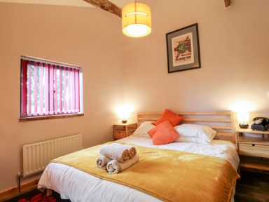 A bedroom with a double bed two bedside tables lamps and a window with vertical blinds at Elvan Cottage in Liskeard