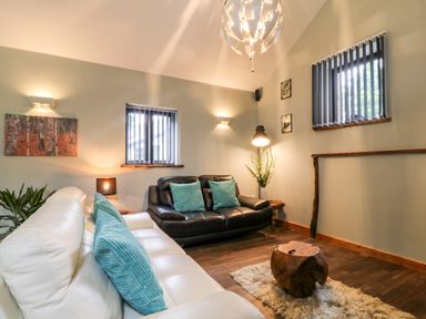 A living room with two sofas wooden coffee table and plants at Elvan Cottage in Liskeard