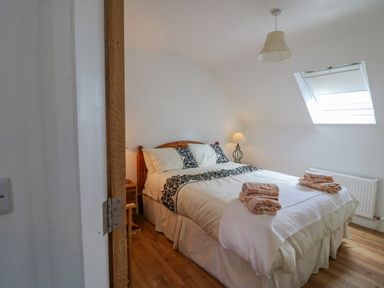 A bedroom with a double bed towels on the bed and a bedside lamp at Beehive Cottage in Kilbrittain County Cork