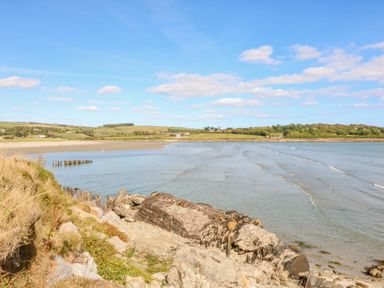 A coastal landscape with a beach grassy hills and scattered houses at Beehive Cottage in Kilbrittain County Cork