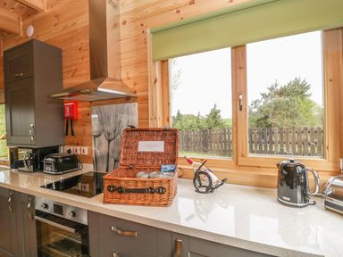 A kitchen countertop with a toaster kettle wine bottle and basket near a window at Sunnyside Lodge in Crewkerne