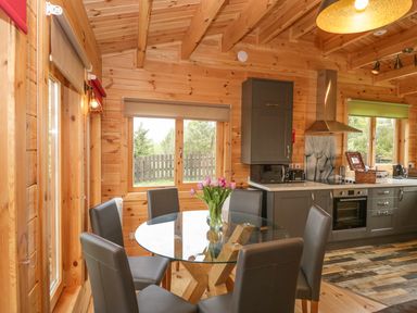 A kitchen and dining area with a glass round table and gray chairs at Sunnyside Lodge in Crewkerne
