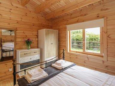 A bedroom with a bed folded towels a wardrobe a chest of drawers with flowers and a window at Sunnyside Lodge in Crewkerne