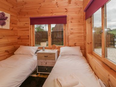 A small bedroom with two single beds and a nightstand between them at Sunnyside Lodge in Crewkerne