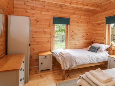 A bedroom with two single beds bedside tables a wardrobe and windows at Sunnyside Lodge in Crewkerne