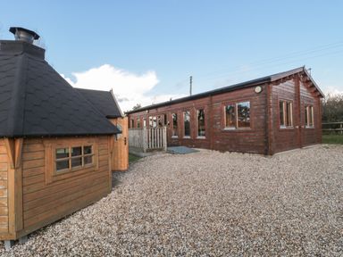 An exterior view of two wooden buildings on a gravel surface at Sunnyside Lodge in Crewkerne
