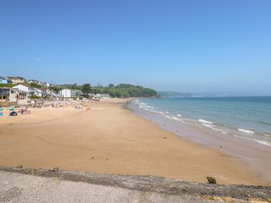 A sandy beach with people and buildings along the shore by the sea at 4 Hanbury Lodge in Pentlepoir
