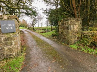 A stone driveway entrance with two stone pillars and trees along the path at 4 Hanbury Lodge in Pentlepoir
