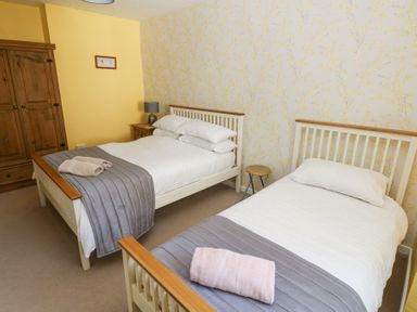 A bedroom with two beds one double and one single with towels on each at 4 Hanbury Lodge in Pentlepoir