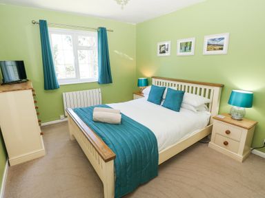 A bedroom with a bed chest of drawers bedside tables and a window at 4 Hanbury Lodge in Pentlepoir