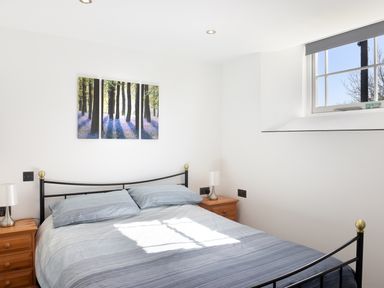 A bedroom with a double bed two bedside tables with lamps and a triptych forest artwork on the wall at Moor View Chapel in Camelford