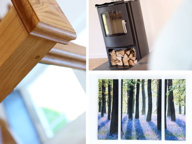 A close-up of a wooden staircase railing a black stove with firewood below and a three-panel wall art of a forest at Moor View Chapel in Camelford