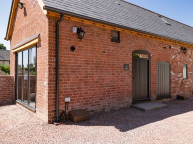 A brick building with black doors and large windows at The Stables in Cross Keys near Hereford