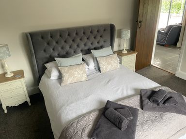 A bedroom with a bed with pillows and folded towels with bedside tables with lamps at The Stables in Cross Keys near Hereford
