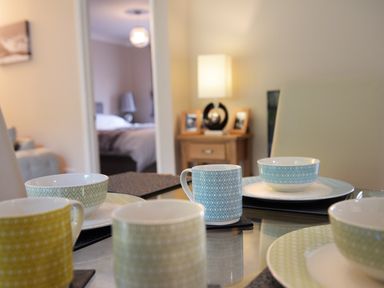 A dining table set with patterned cups and bowls with a bedroom visible in the background at Little Retreat in Liskeard