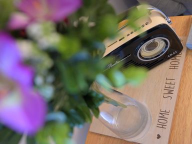 A vintage radio on a wooden board with the words home sweet home next to a glass vase with flowers at Little Retreat in Liskeard