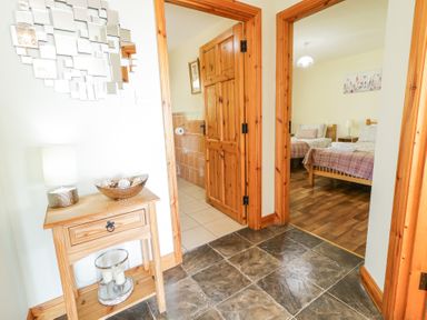 A hallway with wooden doors leading to a bathroom and a bedroom with twin beds at Tullyally in Redcastle
