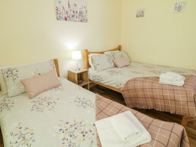 A bedroom with two single beds and a small wooden nightstand with a lamp at Tullyally in Redcastle