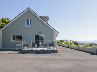 A house with a small patio with chairs and flowerpots overlooking a rural landscape at Tullyally in Redcastle