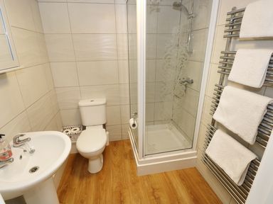 A bathroom with a sink toilet shower and towel rack with towels at The Granary Cottage in Llangrannog near Cardigan