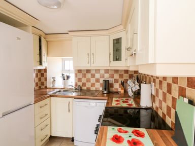 A kitchen with cream cabinets a white refrigerator a dishwasher a sink and a stove with poppy flower mats at Grange Farmhouse in Fethard-on-Sea County Wexford