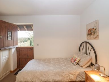 A bedroom with a bed a wooden half door a nightstand and a painting of a fox at The Old Goat Barn at Trout Cottage in Somerton