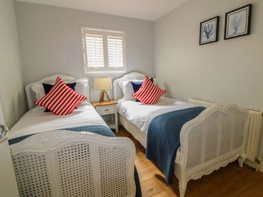 A bedroom with two single beds with striped pillows a nightstand and lamp between them at Oh Buoy in Charlestown