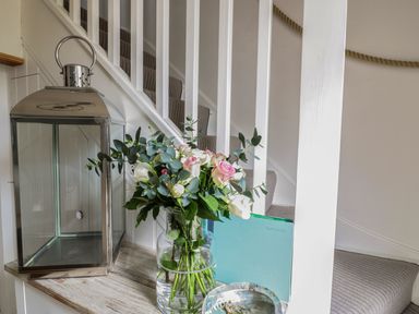 A staircase with a metal lantern a vase with flowers a guest book and a small dish on a wooden shelf at Oh Buoy in Charlestown