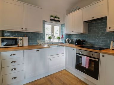 A kitchen with white cabinets wooden countertops a window above a sink a microwave oven and various small appliances at Oh Buoy in Charlestown