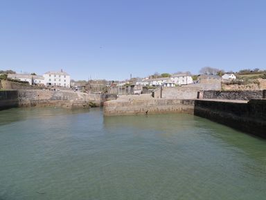 A harbor with stone walls, water, boats, and white buildings in the background at Oh Buoy in Charlestown