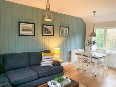 A living room with a dark sofa and dining table with white chairs at Oh Buoy in Charlestown