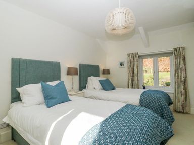 A bedroom with two single beds and blue cushions at Clamoak Cottage in Clamoak near Bere Alston