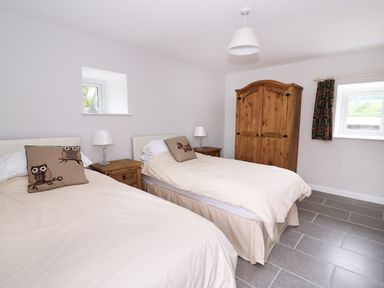 A bedroom with two single beds wooden nightstands and a wardrobe at Cilgwyn Bach in Llandysul