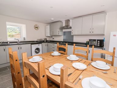 A kitchen with wooden dining table set for six and grey cabinets at Cilgwyn Bach in Llandysul
