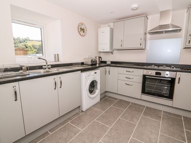 A kitchen with a window sink washing machine oven and stove at Cilgwyn Bach in Llandysul