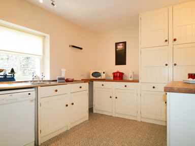 A kitchen with white cabinets wooden countertops a microwave and a window at Dale House in Lorton