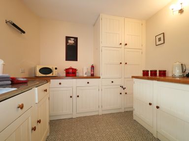 A kitchen with white cabinets a microwave a red bread bin and red jars at Dale House in Lorton