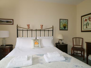 A bedroom with a double bed with white linens and towels a wooden chair and framed pictures on the walls at Dale House in Lorton