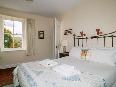 A bedroom with a bed covered in a quilt and towels on top with a window showing trees and hills at Dale House in Lorton